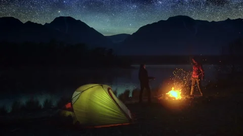 Father and son nature camping, campfire in the mountains near pond at night. Stock Footage 261784953