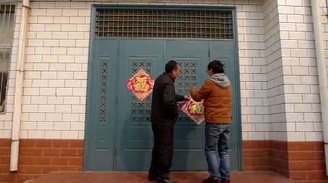 Father and son pasting spring couplet “fu”, means happiness, on new year Stock Footage 34838197