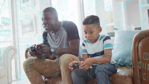 Father and son picking up controllers, playing on couch, binary-code overlay Stock Footage 333233062