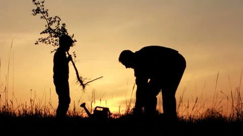 Father and son planting a tree. Sunrise. Silhouette. Spring. Stock Footage