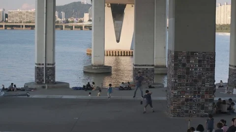 Father and son play catch at Han River with bridge  in background Stock Footage 114854600