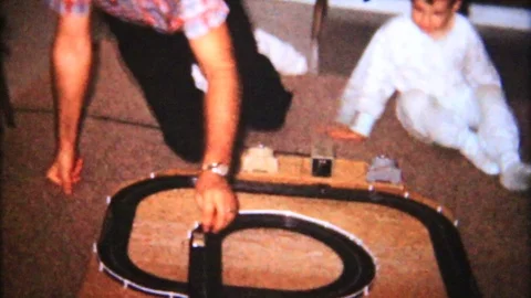 Father and son play with electric slot car track 1950s vintage home movie 5607 Stock Footage