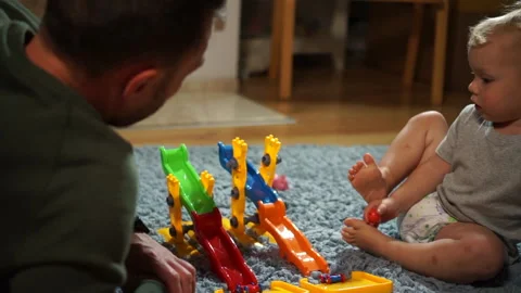 Father and Son play with a plastic blocks while sitting on the carpet in the Stock Footage 141148784
