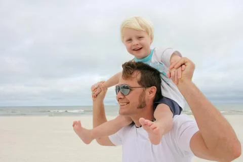 Father and son playing on beach by ocean Stock Photos