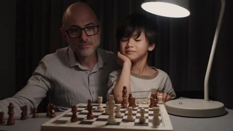 Father and son playing chess at home child wins checkmate and father reacts Stock Footage 331093156