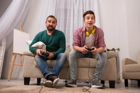Father and son playing in the console at home. Stock Photos