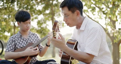 Father and son practice playing guitar with enthusiasm, happy relaxing  Stock Footage 166906269