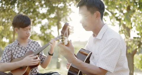 Father and son practice playing guitar with enthusiasm, happy relaxing  Stockbeeldmateriaal 166906404