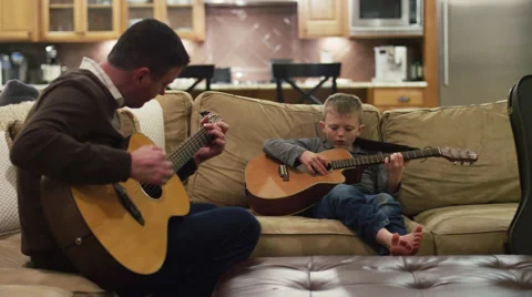 Father and son practicing on their guitars in the living room Stock Footage 63262462