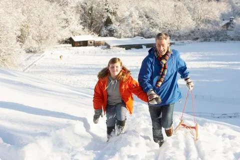Father and son pulling sledge up snowy hill Stock Photos