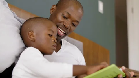 Father and son reading in bed Video stock 119612954