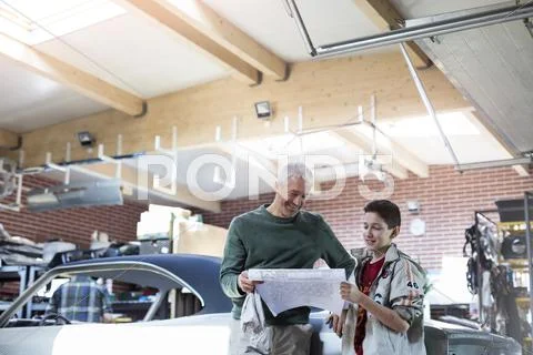 Father and son reviewing plans in auto repair shop Stock Photos