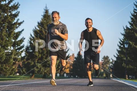 The father and a son running on the park road Stock Photos