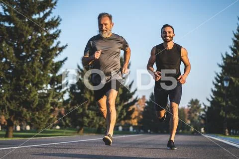 The father and a son running on the park road Stock Photos