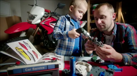 Father and Son Screwing Wheels to the Toy Car Stock Footage 62216564