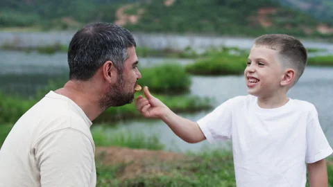 Father and son share pizza on picnic. Stock Footage 288423926