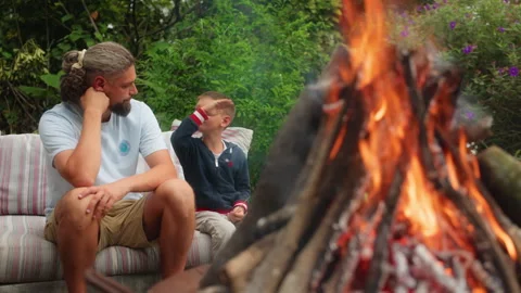Father and Son Sitting by Campfire in Backyard Garden During Summer Evening. Stock Footage 338371008