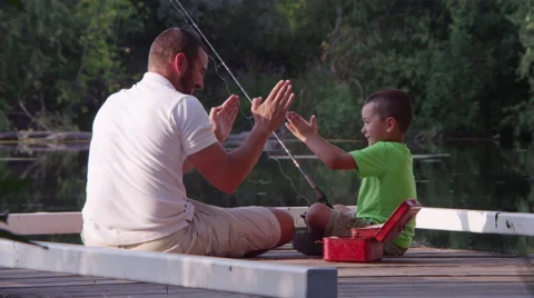 Father and son sitting on dock with fishing pole Stock Footage 67299097