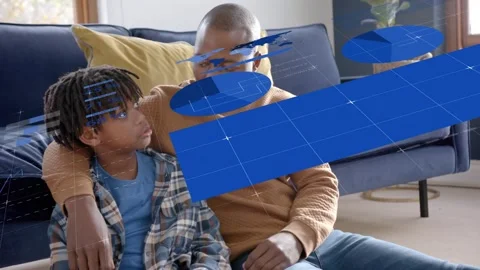 Father and son sitting on floor demoing tech while boy speaking causing blue HUD Stock Footage 333774842