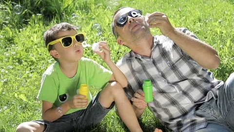 Father and son sitting on the grass in the park at the day time.  Stock Footage 79506198