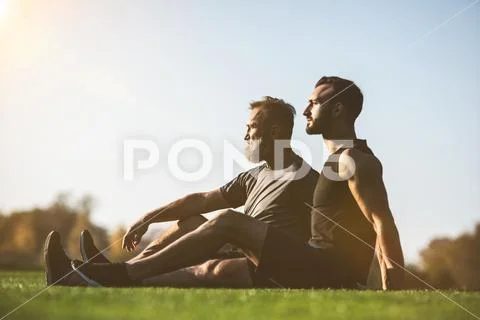 The father and a son sitting on the grass on the sunny background Stock Photos