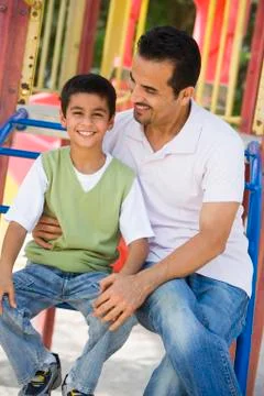 Father and son sitting on playground structure smiling (selective focus) Fotos de archivo