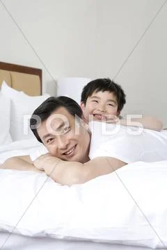 Father and son smiling on bed Stock Photos