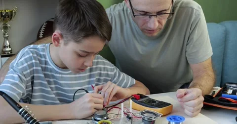 Father and son spend quality time together at home working on electronics Stock Footage 346764925