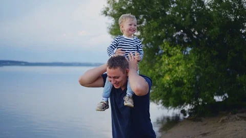 Father and son spend time together, have fun outdoors in a park by the lake Stock Footage 116765783
