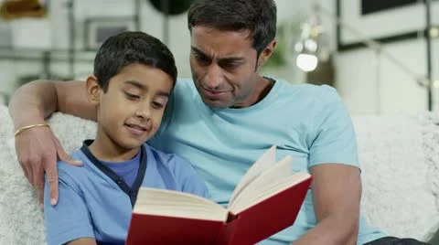 Father and son spending time together at home, reading a book Stock Footage 12679408