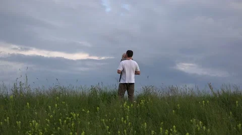 Father and son in spring hill top, baby close to dramatic sky 4K Stock Footage 46206079