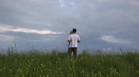 Father and son in spring hill top, baby close to dramatic sky  Stock Footage 46206745
