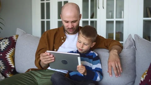 Father and son study together man holds tablet boy plays spbd Stock Footage 165198889