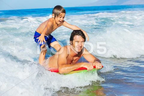 Father and son surfing tandem togehter catching ocean wave Stock Photos