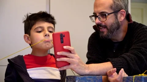Father and son taking funny selfies during Christmas gift wrapping Stock Footage 345253264