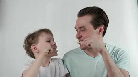 Father and son teeth brushing. Dad and his son brush his teeth at white Stock Footage 171750152