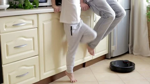 Father and Son testing the Robotic Vacuum Cleaner clean up the floor Stock Footage 163444593
