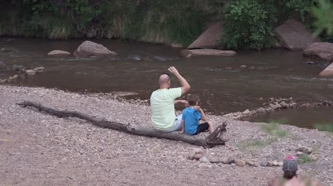Father and son throwing rocks into river Stock Footage 43386612
