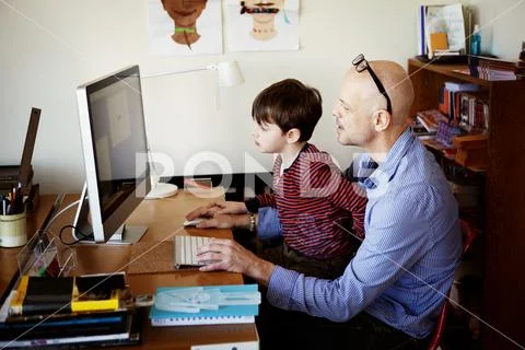 Father and son using desktop computer while sitting at table Stock ...