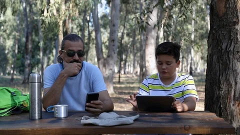 Father and son using digital tablet and smartphone at the nature 2 Video stock 95561089