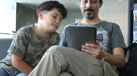 Father and son using i pad at the airport Stock Footage 53143851