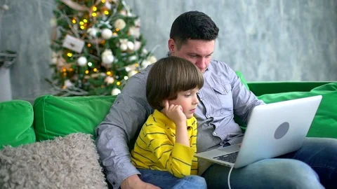 Father and son using laptop. Handsome father looking at computer with very cute Stock Footage 83435468