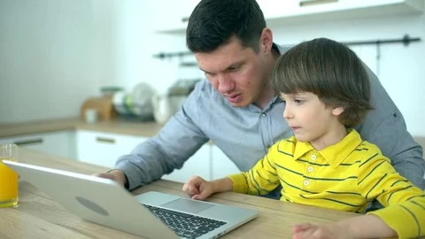 Father and son using laptop. Handsome father looking at computer with very cute Stock Footage 83435688