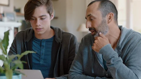 Father and son using laptop computer dad helping teenage boy with homework at Stock Footage 113256003