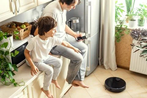 Father and Son Using Robotic Vacuum Cleaner Stock Photos