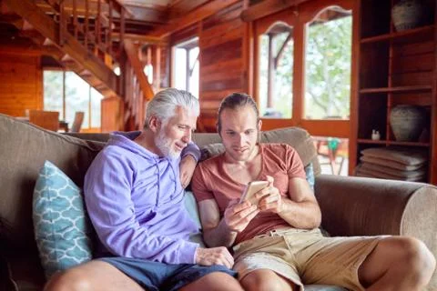 Father and son using smart phone on cabin sofa Stock Photos