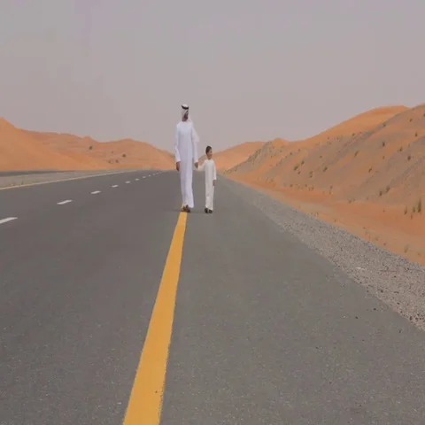 Father and son walking down the desert highway. Stock Footage 69484599
