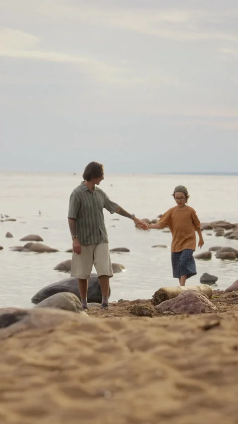 Father and Son Walking on Rocky Beach Holding Hands Together Stock Footage 340265832