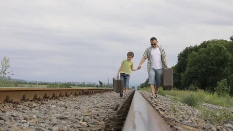 Father and son walking with suitcases on the railway at the day time. Stock Footage