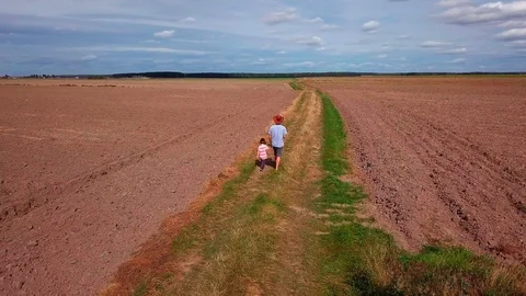 Father and son walking through sandy road on fields. 4k AERIAL footage. Stock Footage 95027397